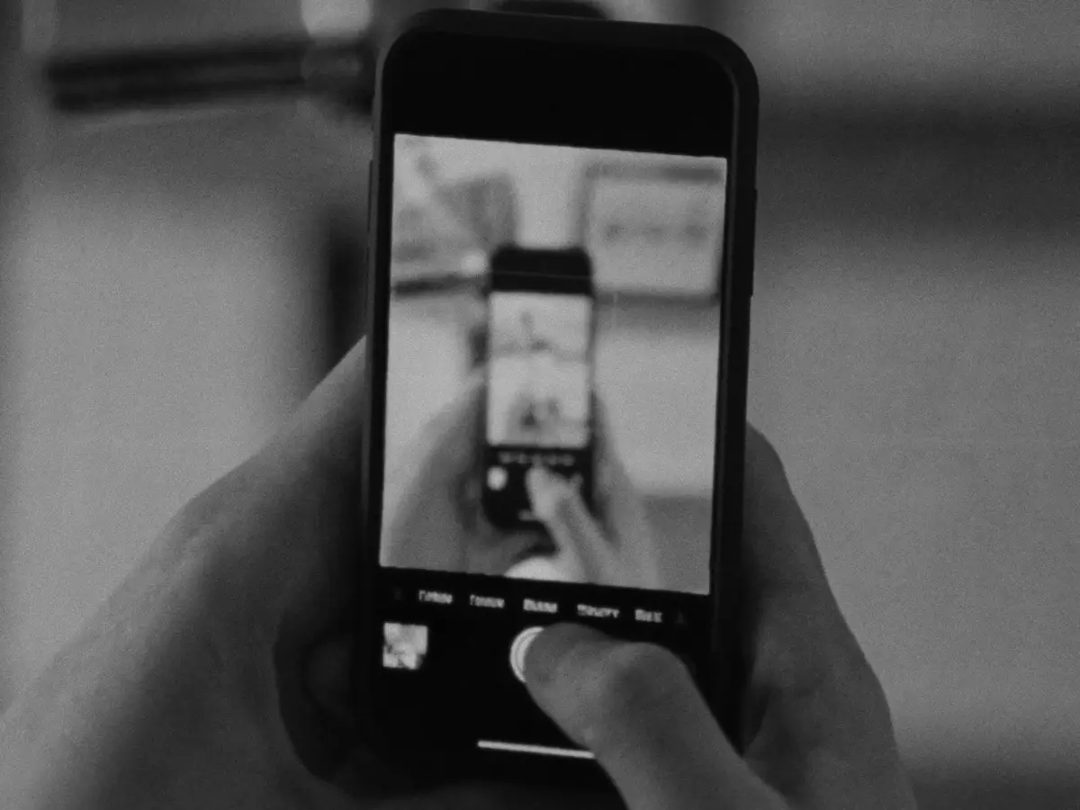 Main tenant un téléphone qui filme la scène